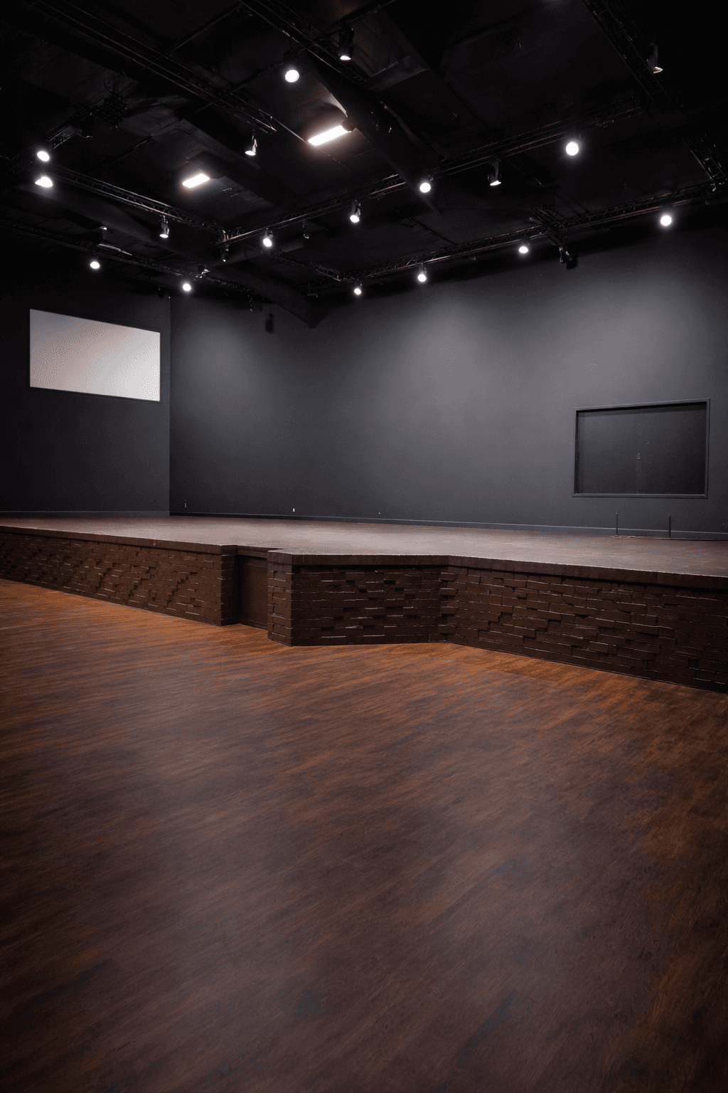 A modern, luxury beachfront villa with large glass windows and balconies overlooks a rocky shoreline, surrounded by palm trees at sunset.