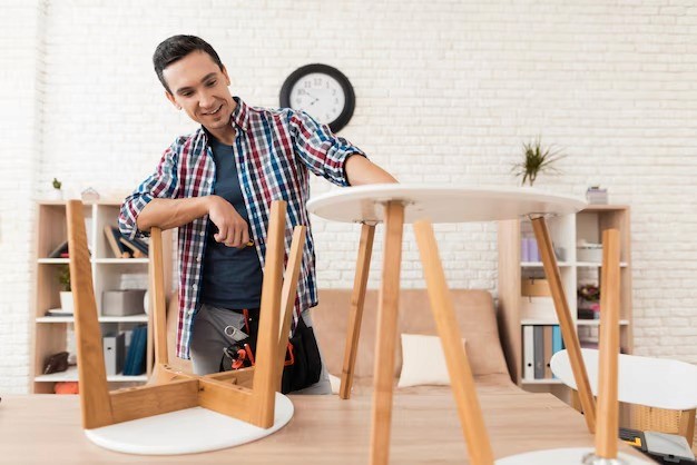 Man assembling a round table, focused on the task with a smile. Furniture assembly and DIY concept.
