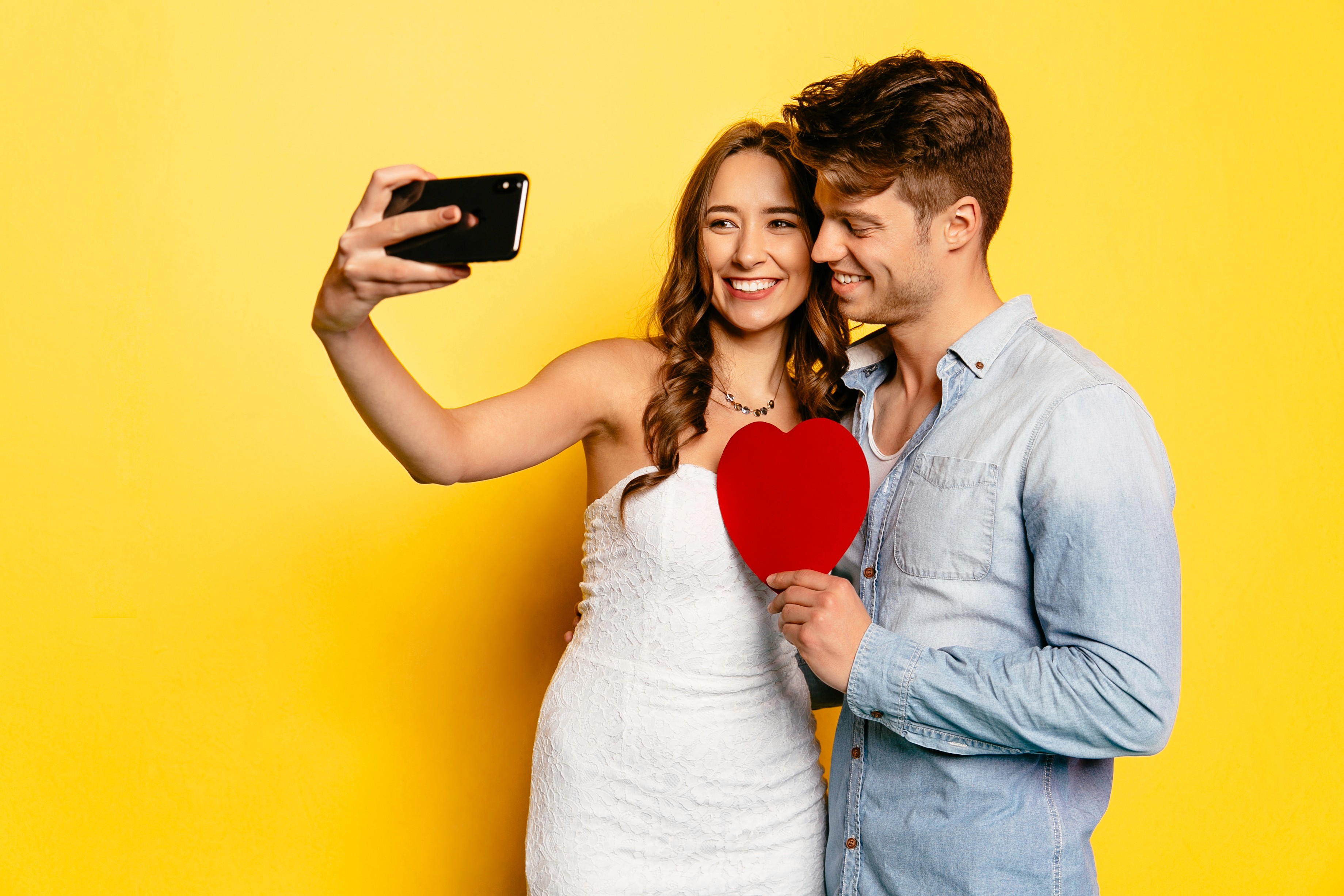 Couple taking a Valentine’s Day selfie with a heart prop, showcasing romantic TikTok video ideas that boost engagement and gifting inspiration.