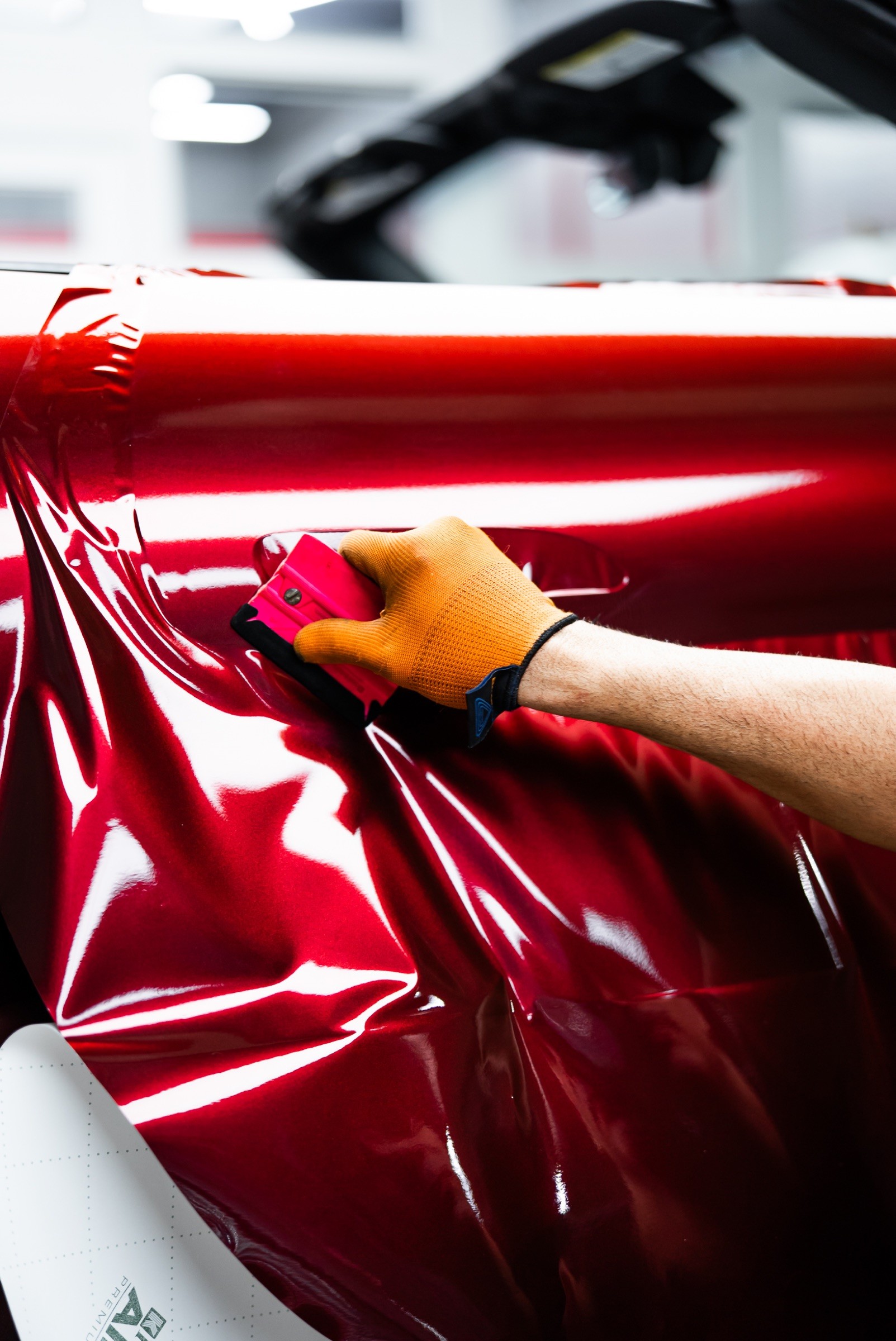 Applying a candy red vinyl wrap to a Porsche door