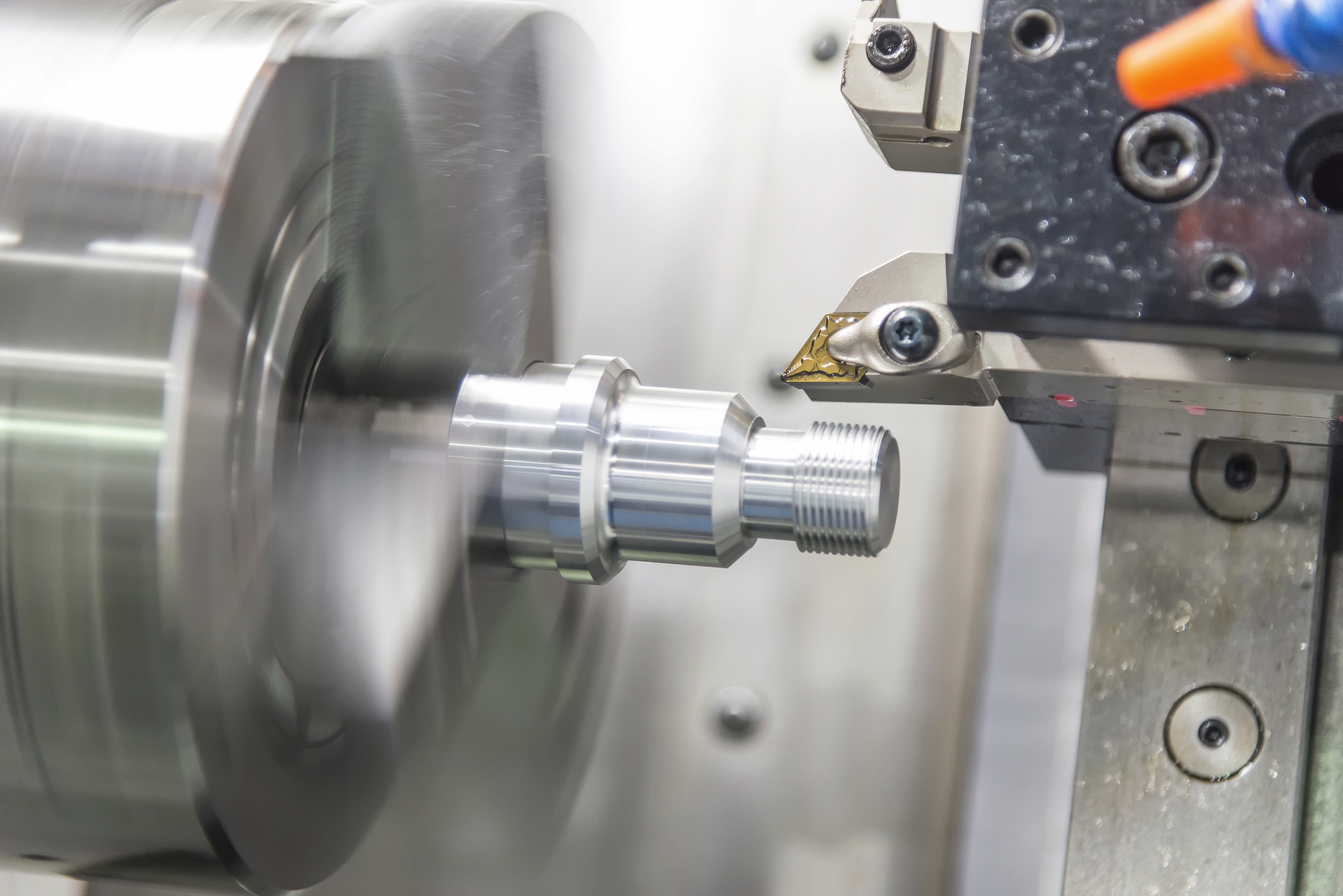 Close-up of a lathe machine with a workpiece being machined, showing precision equipment and tools in action.