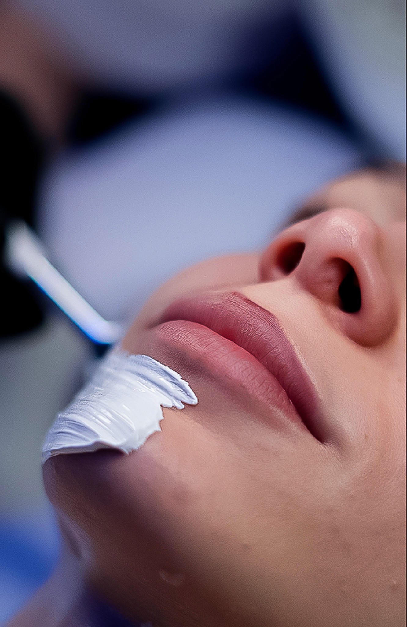 Smiling woman using a rose quartz Gua Sha stone and face roller for a facial massage