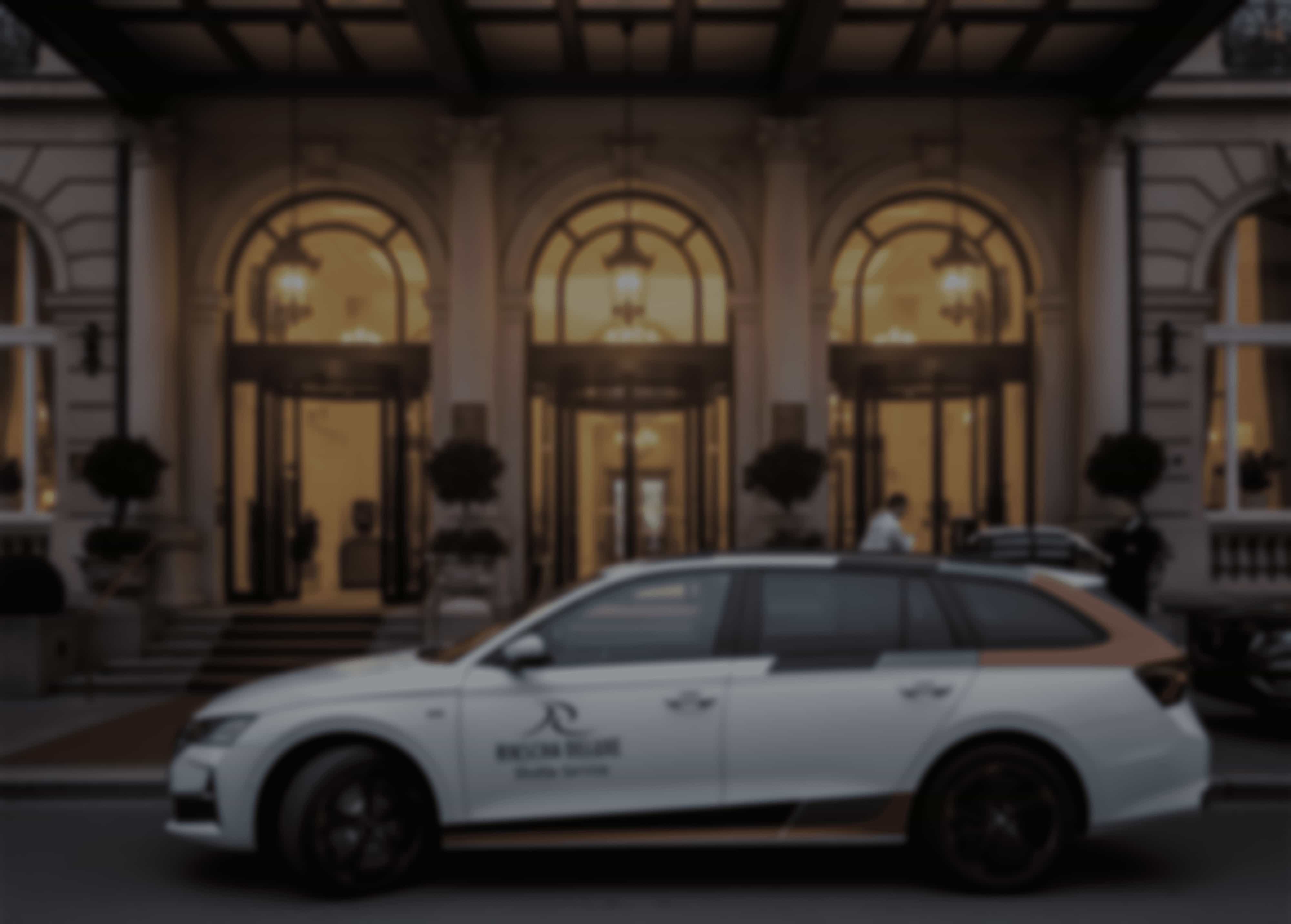 Ein weißer Skoda Octavia Wagen parkt vor einem reich verzierten Gebäude mit Bogeneingängen und leuchtenden Lichtern.