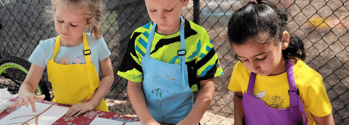 SportPlus campers finger painting at an outside table during art summer camp