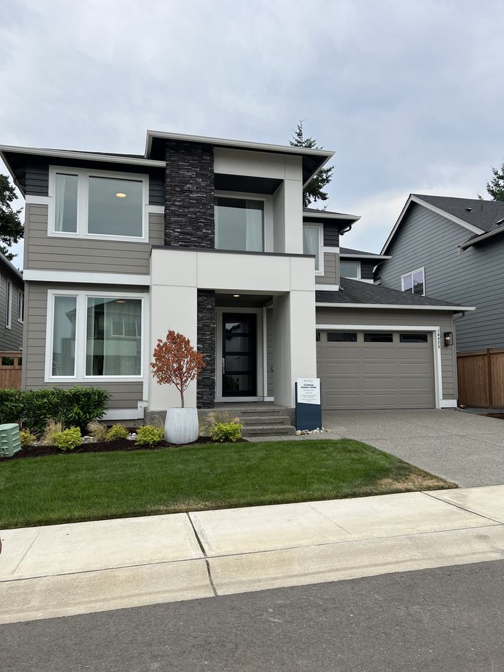 A serene outdoor seating area with two chairs, surrounded by lush greenery and a glassed-in structure.