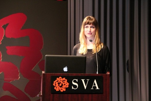 a woman giving a speech from a stand in the "designer as" thesis presentation