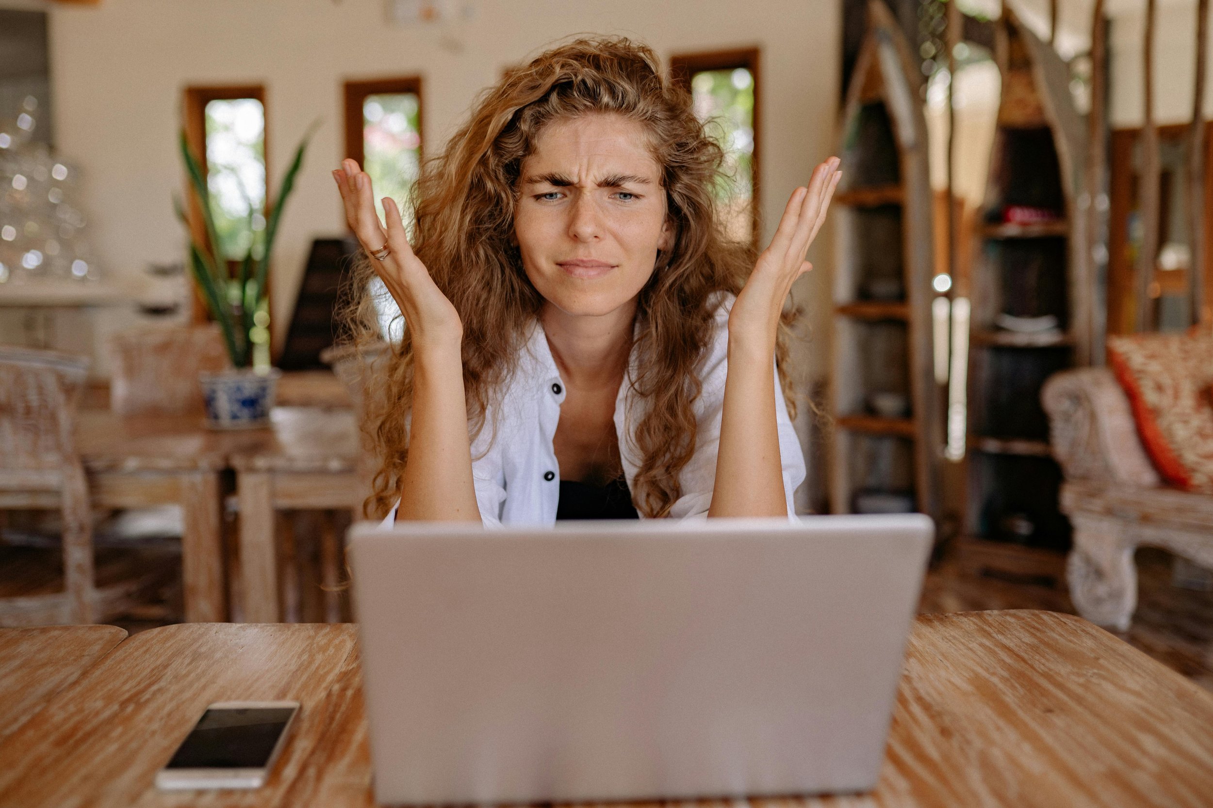 A woman looking frustrated looing at her laptop in a hotel public area
