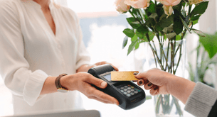 A shopper taps their credit card to a card reader held by the store associate.