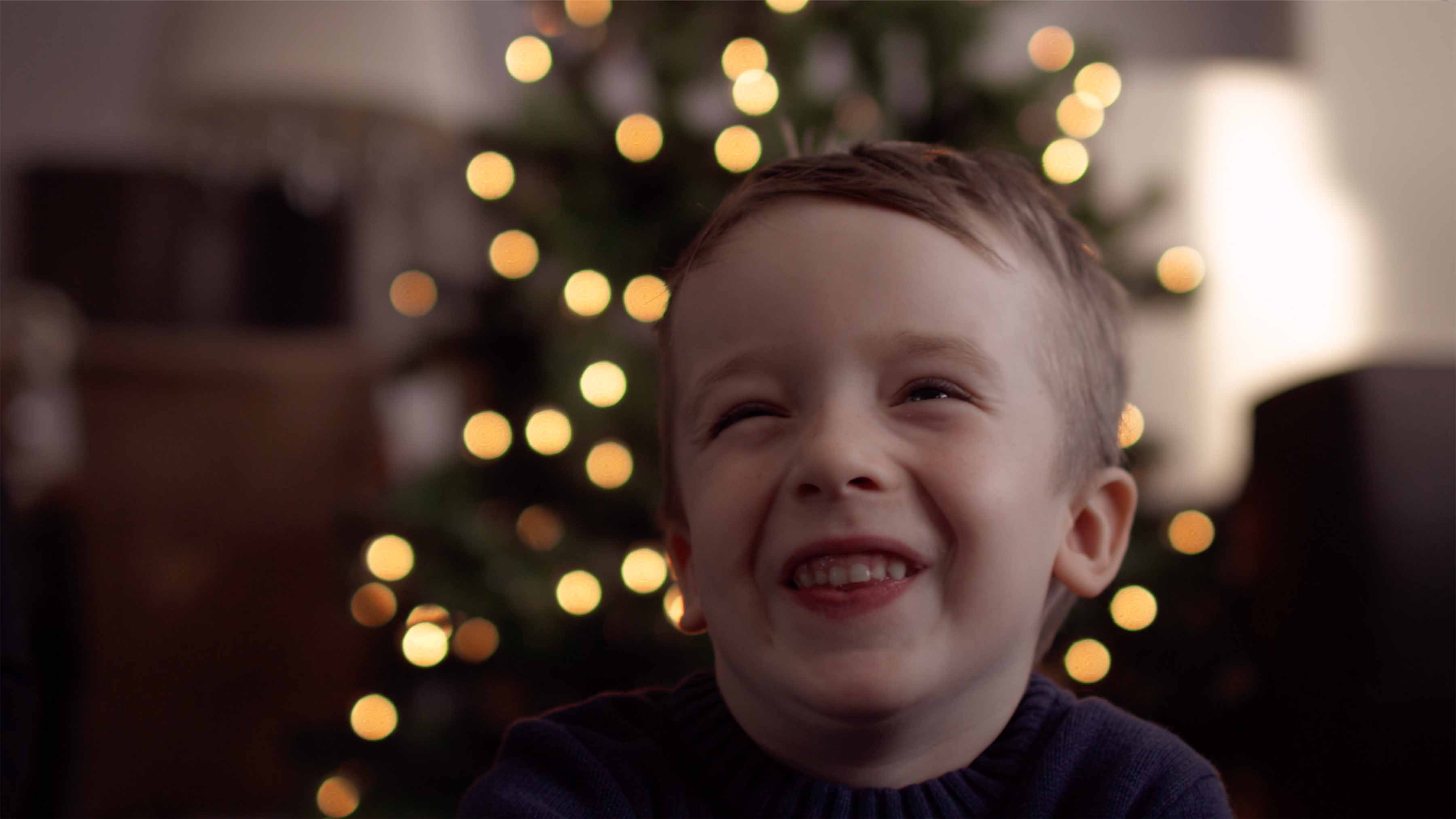 The Benevolent Society Christmas Appeal 2025: a smiling child in front of a lit Christmas tree.