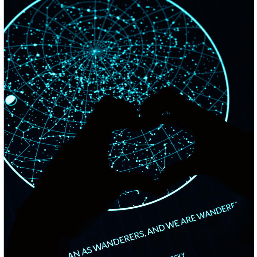 Hands forming a heart in front of a Night Sky Glow in the Dark Star Map. 