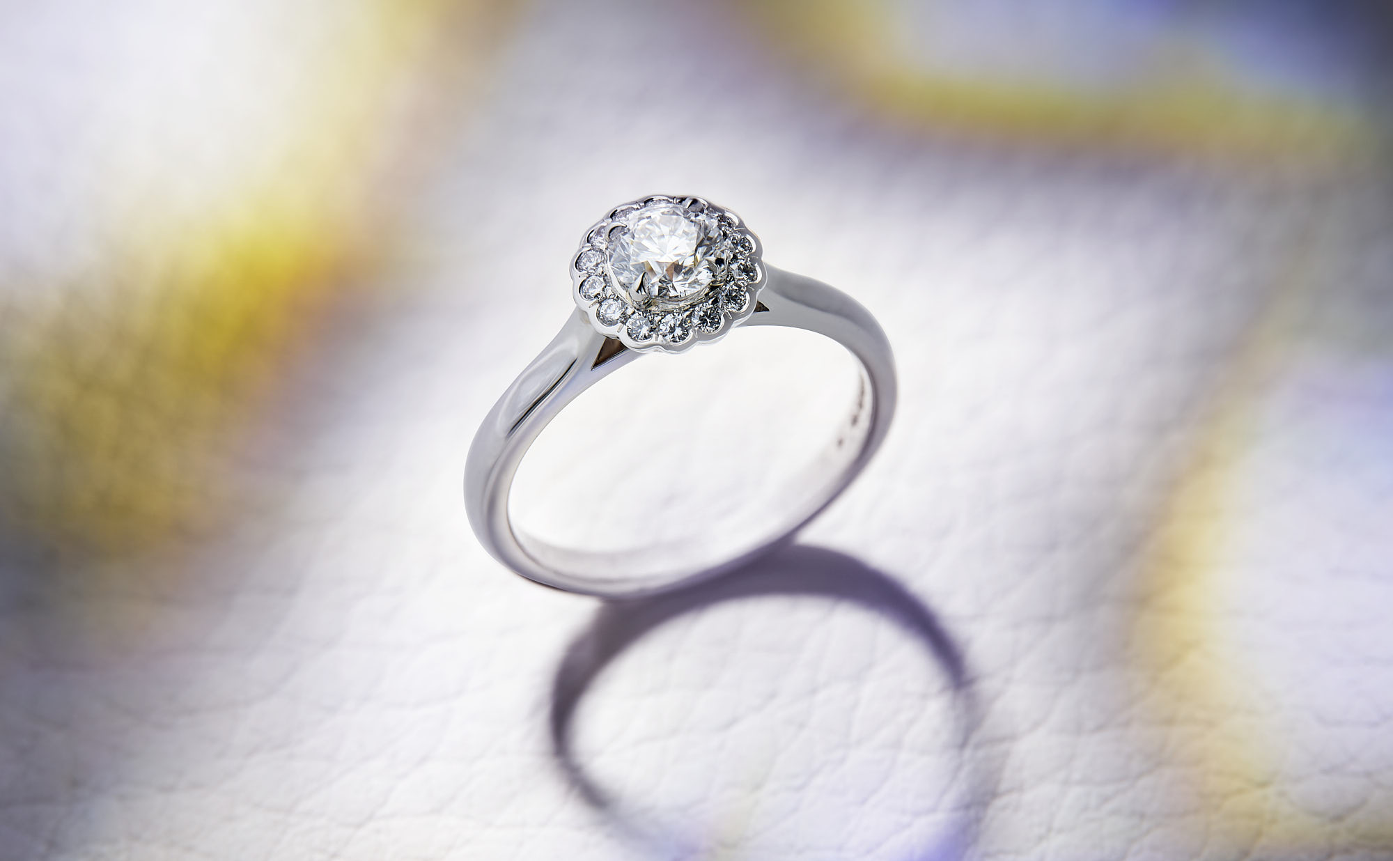 Elegant diamond ring with intricate halo setting on textured background.