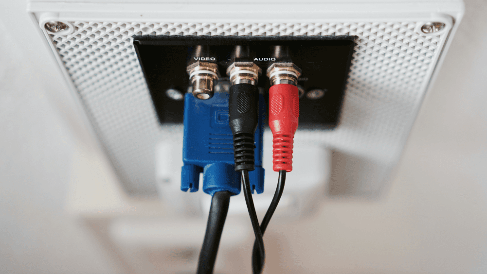 Verschiedenfarbige Kabel, die in ein Gerät gesteckt werden mit Aufschriften Audio, Video und keiner Aufschrift..