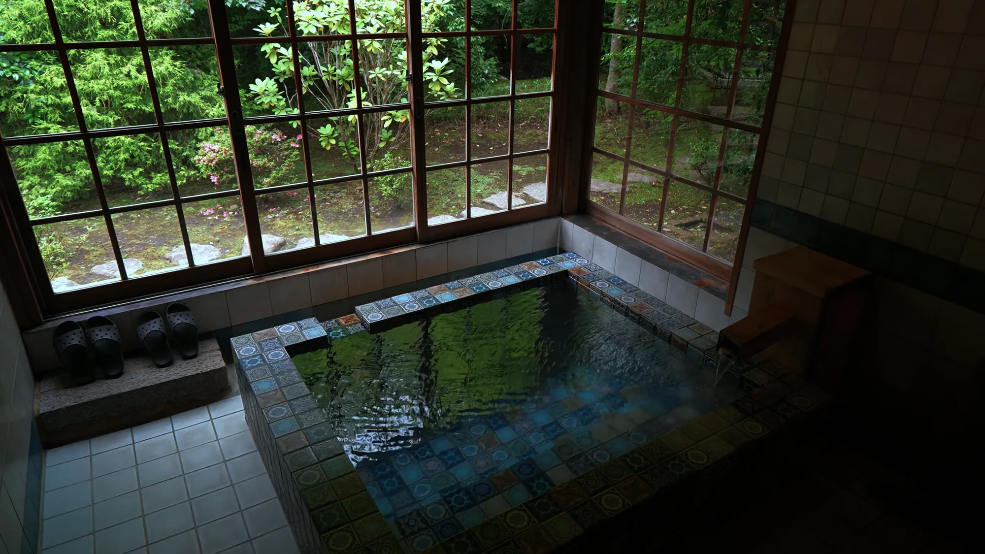 A corner indoor bath with forest windows at a Kurokawa ryokan