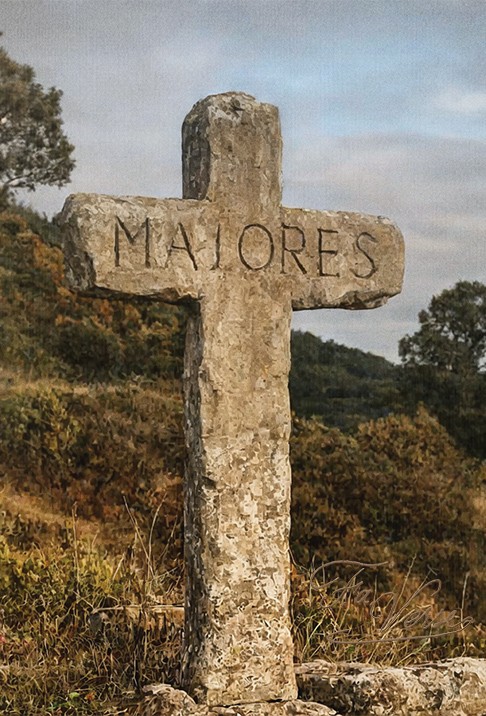Sacred artwork by Faith and Verse. © Faith and Verse, 2025. All rights reserved. Weathered stone cross inscribed with "MAIORES" (ancestors) standing in Bohemian countryside—symbol of early Christian memory and the dynastic faith that Wenceslaus defended
