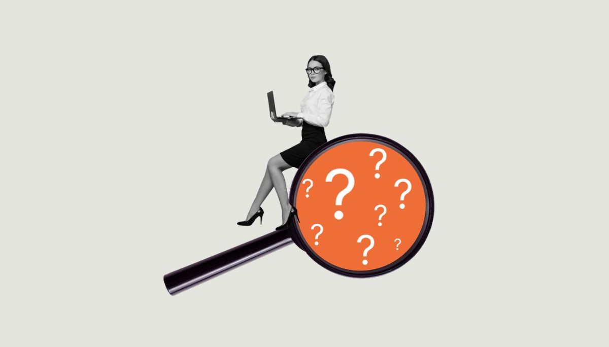 Professional with laptop sitting on magnifying glass filled with question marks, symbolizing hiring manager vs recruiter and why the difference matters.