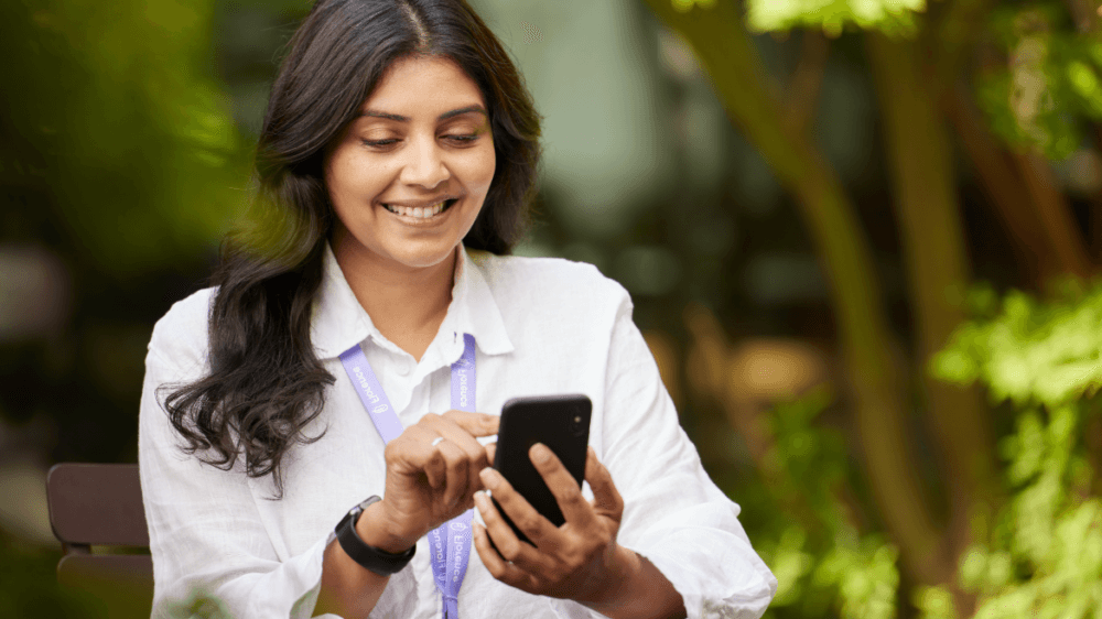 Female manager using mobile phone to manage bank staff and streamline processes with Bank Manager
