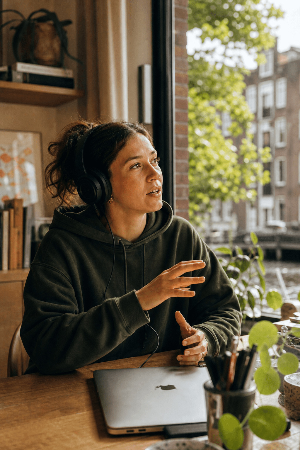 Woman talking in a voice channel, headphones on, closed MacBook on the desk