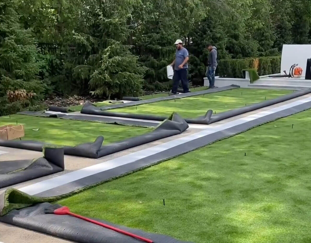 Two AGL Grass North installers roll out synthetic turf for a residential installation.