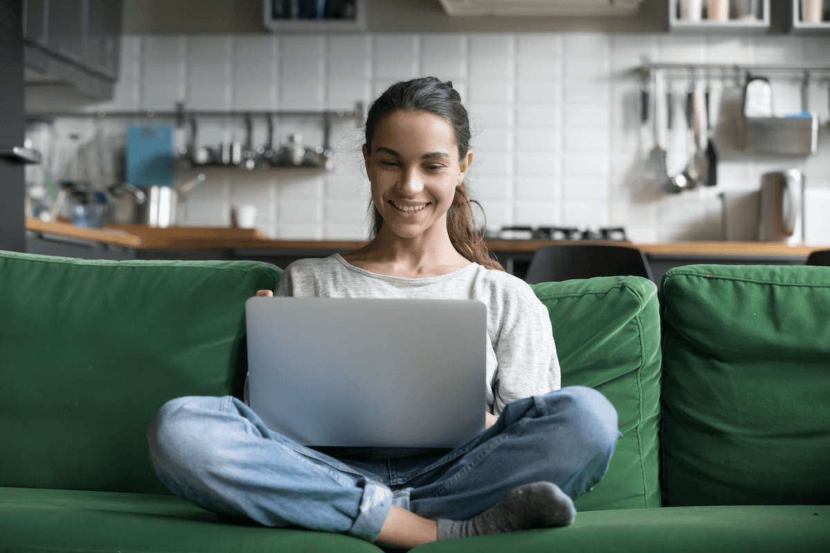 product tour: Smiling woman using her laptop while sitting on her couch