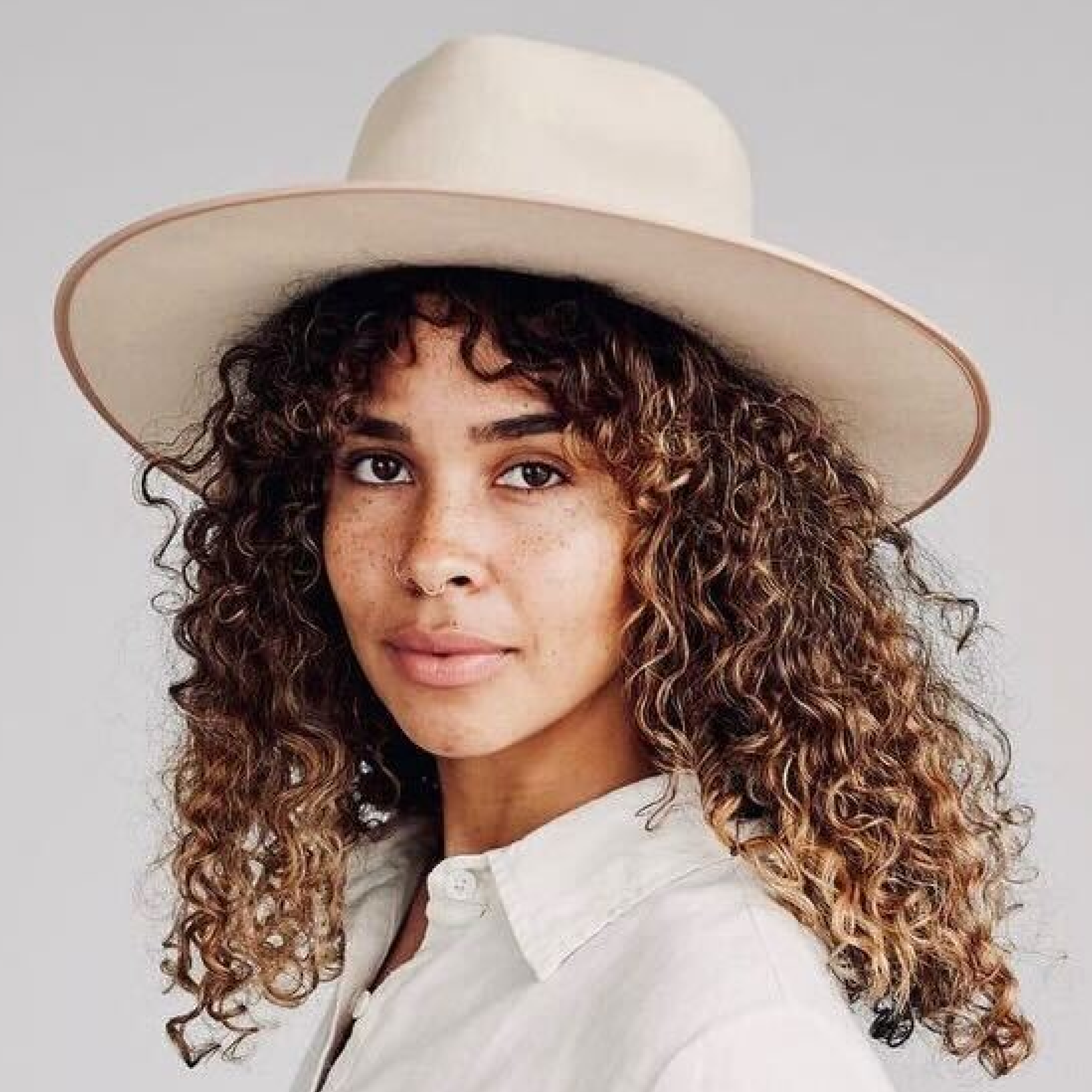 Smiling woman with light brown hair and stubble, wearing a khaki shirt in natural light
