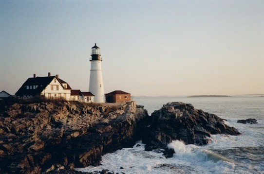 Lighthouse on rocky shore at golden hour