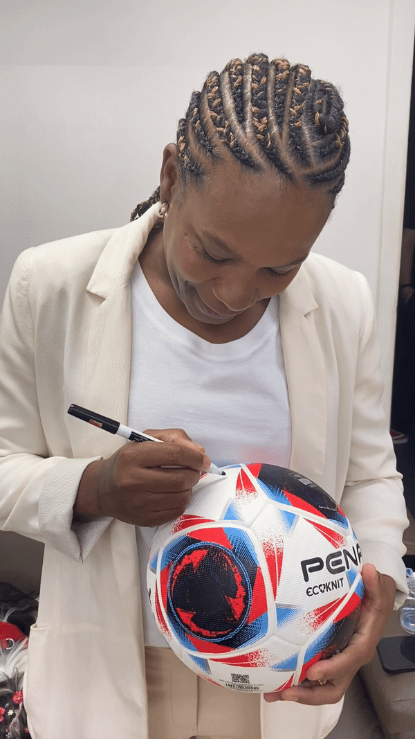 Brazilian football legend Formiga signs a soccer ball for young athletes from the NGO Em Busca de Uma Estrela.