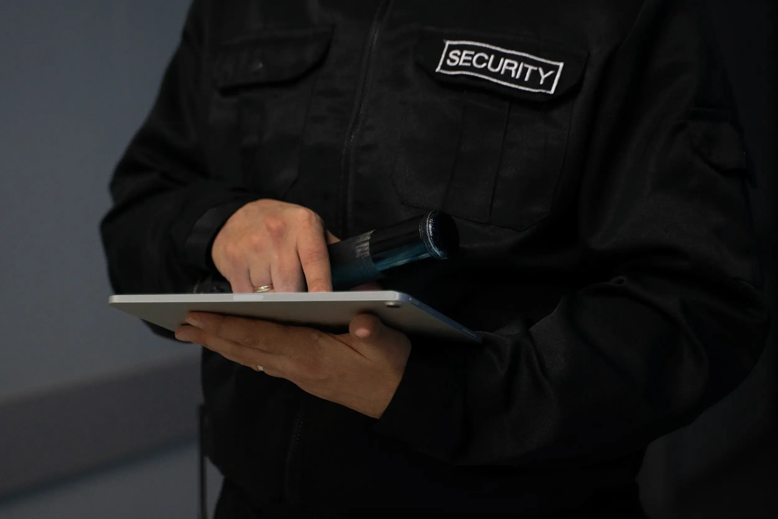 Security professional in tactical uniform conducting threat assessment using digital tablet