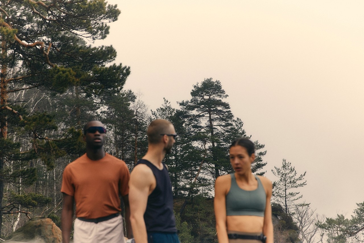 Three hikers walking across a flat mountain plateau with peaks in the background.