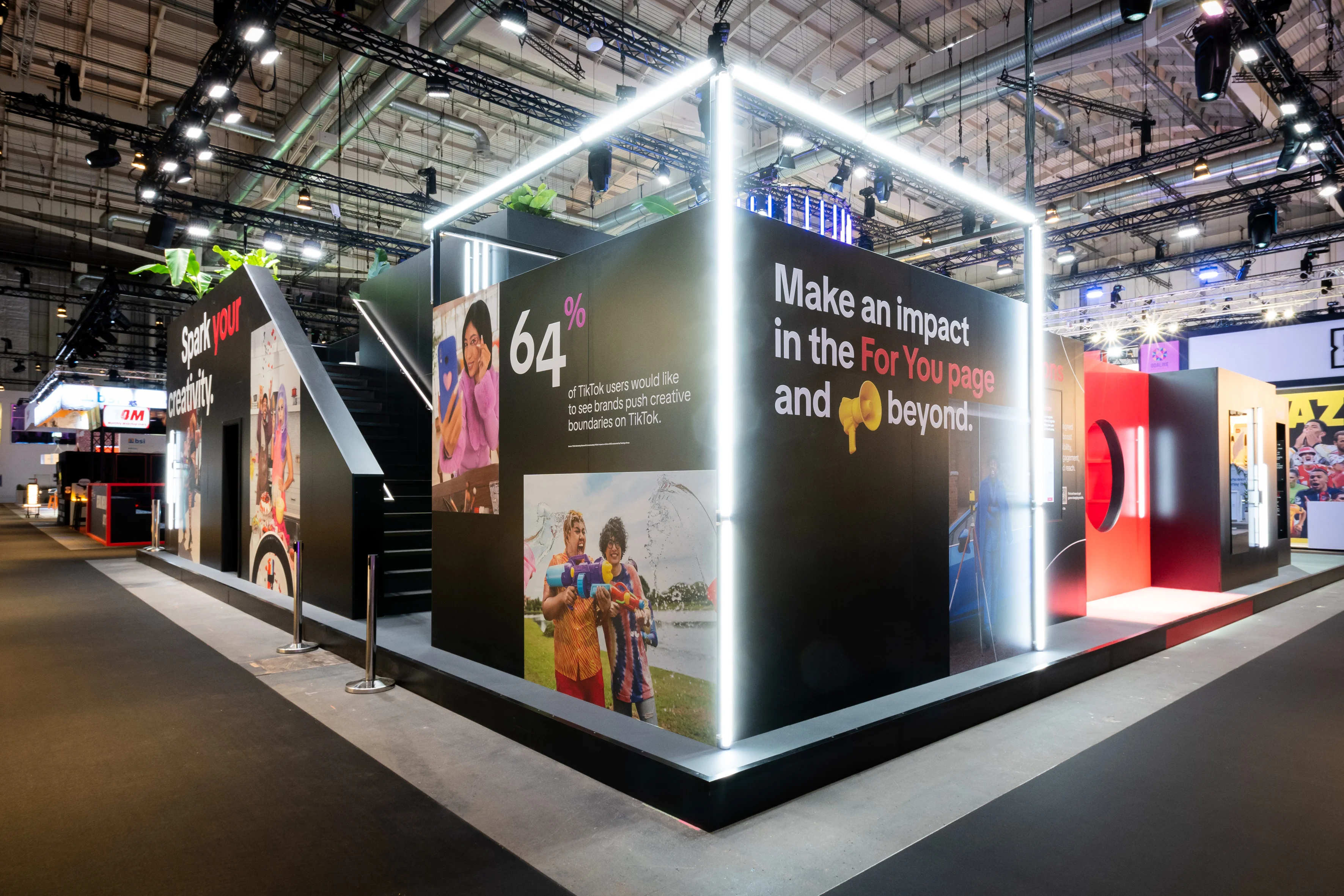 Black TikTok booth cube at OMR with glowing light frame, campaign photos and the slogan Make an Impact in the For You Page.