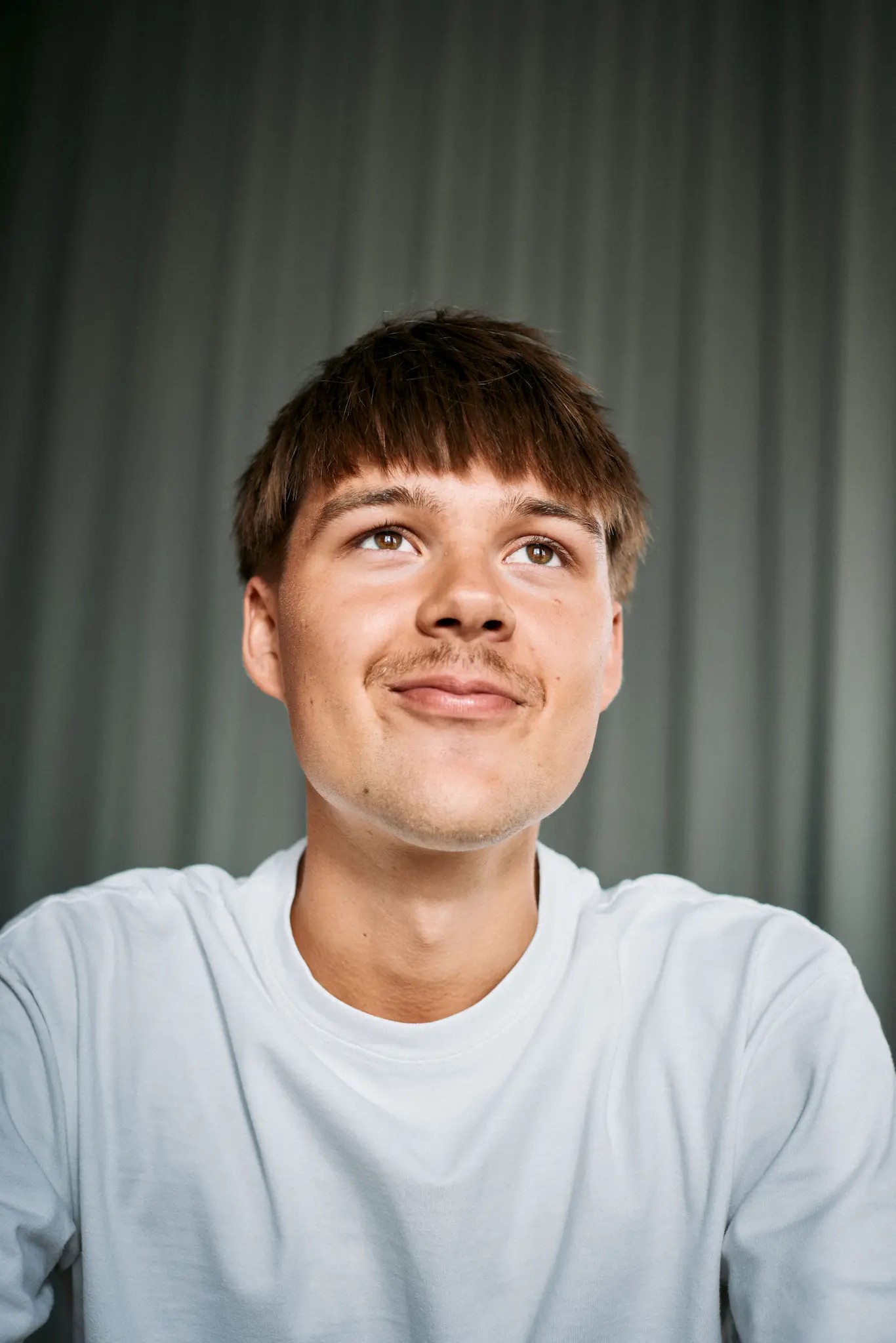 Portrait of a laughing person with curly hair wearing a white shirt