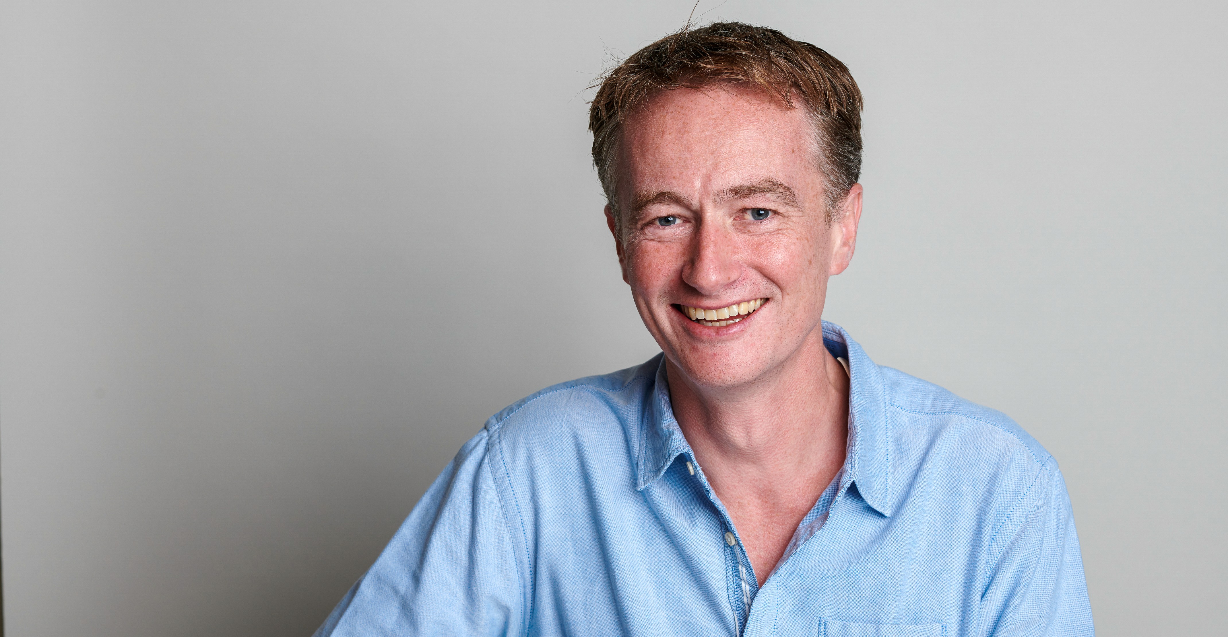 Headshot of Dr Murray Ellender, smiling in a blue shirt