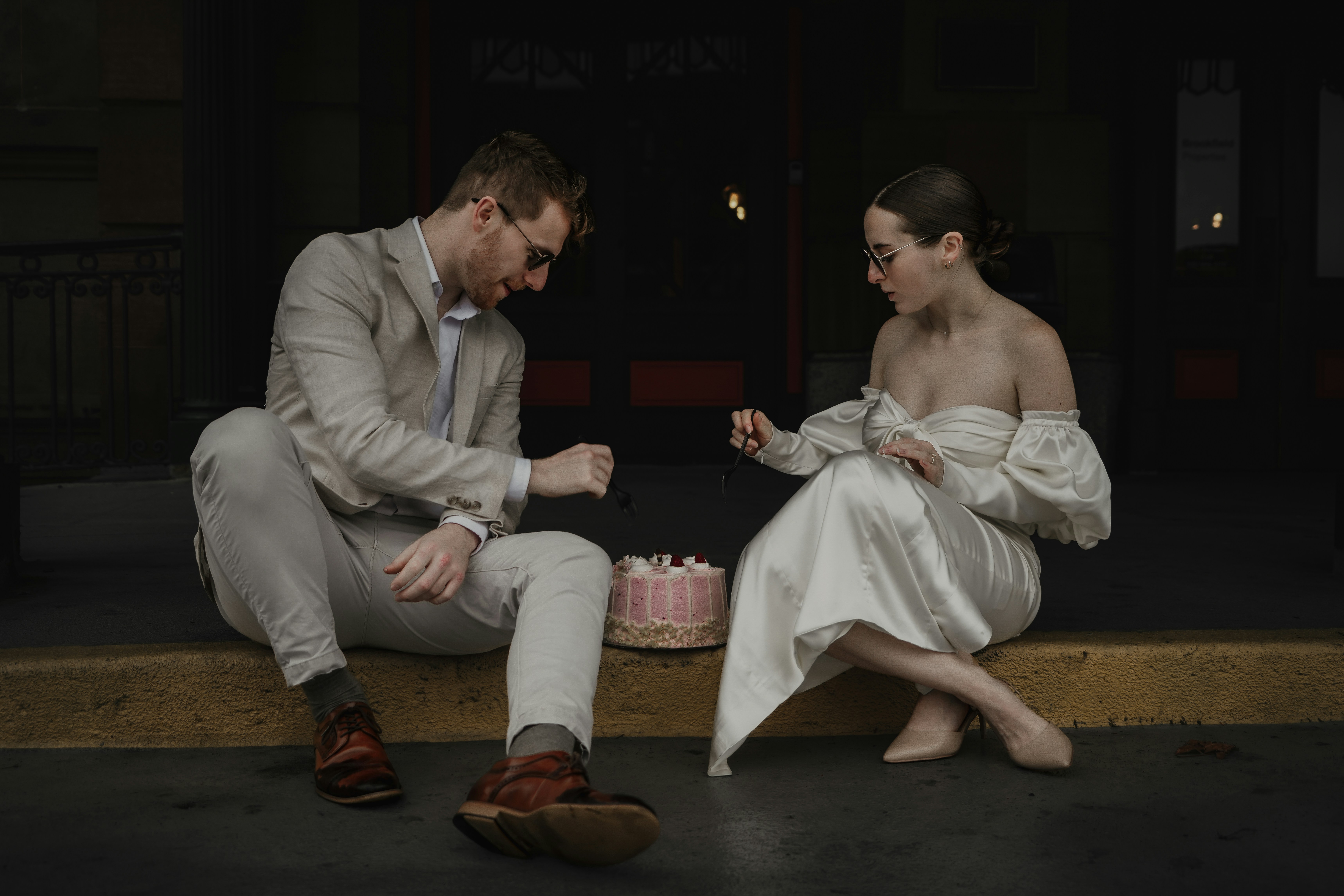 a man and a woman sitting on a bench next to a cake