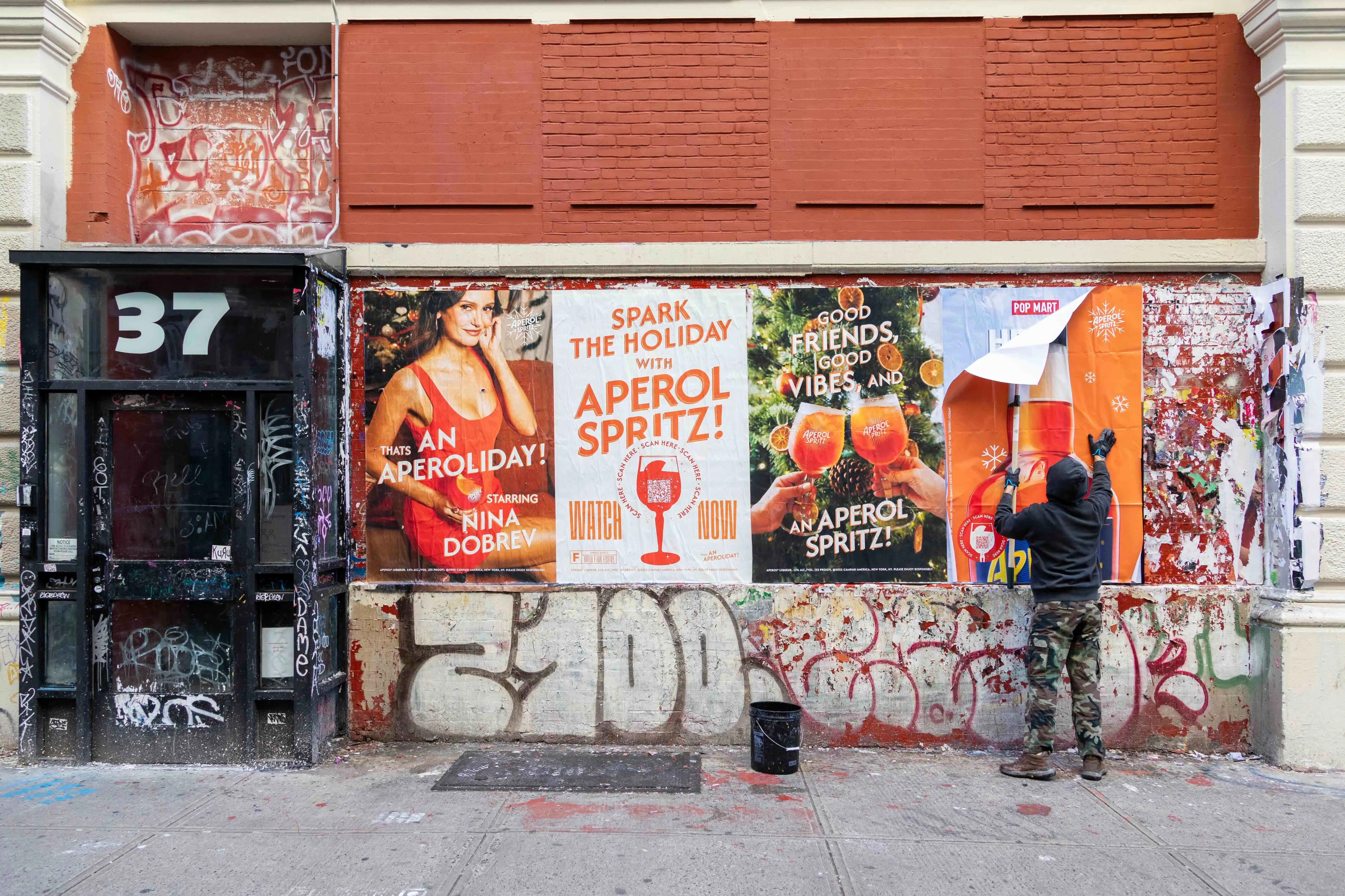 man on new york city sidewalk installing aperol campaign posters