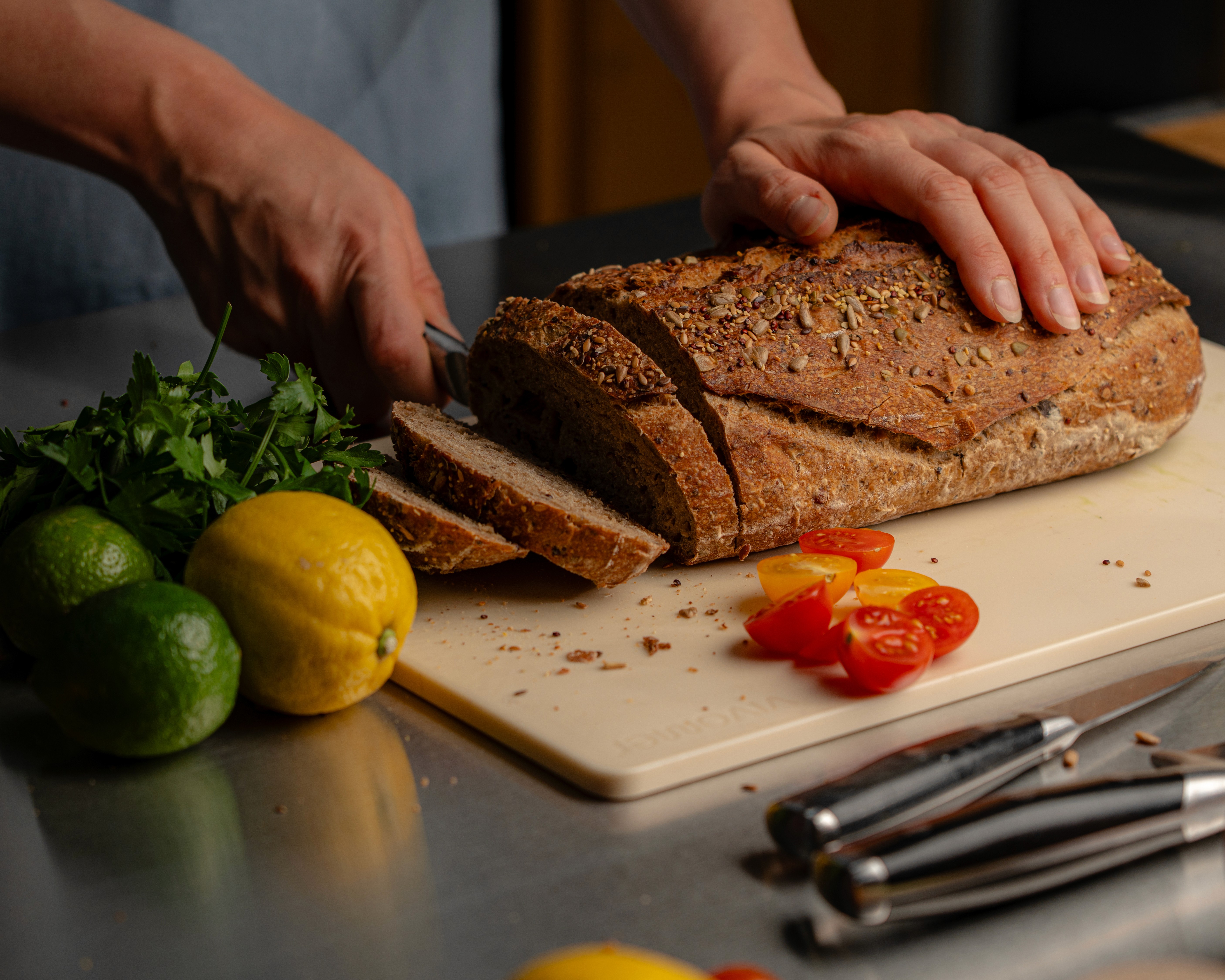 Shellworks VIVOMER cutting board used to slice bread in a kitchen