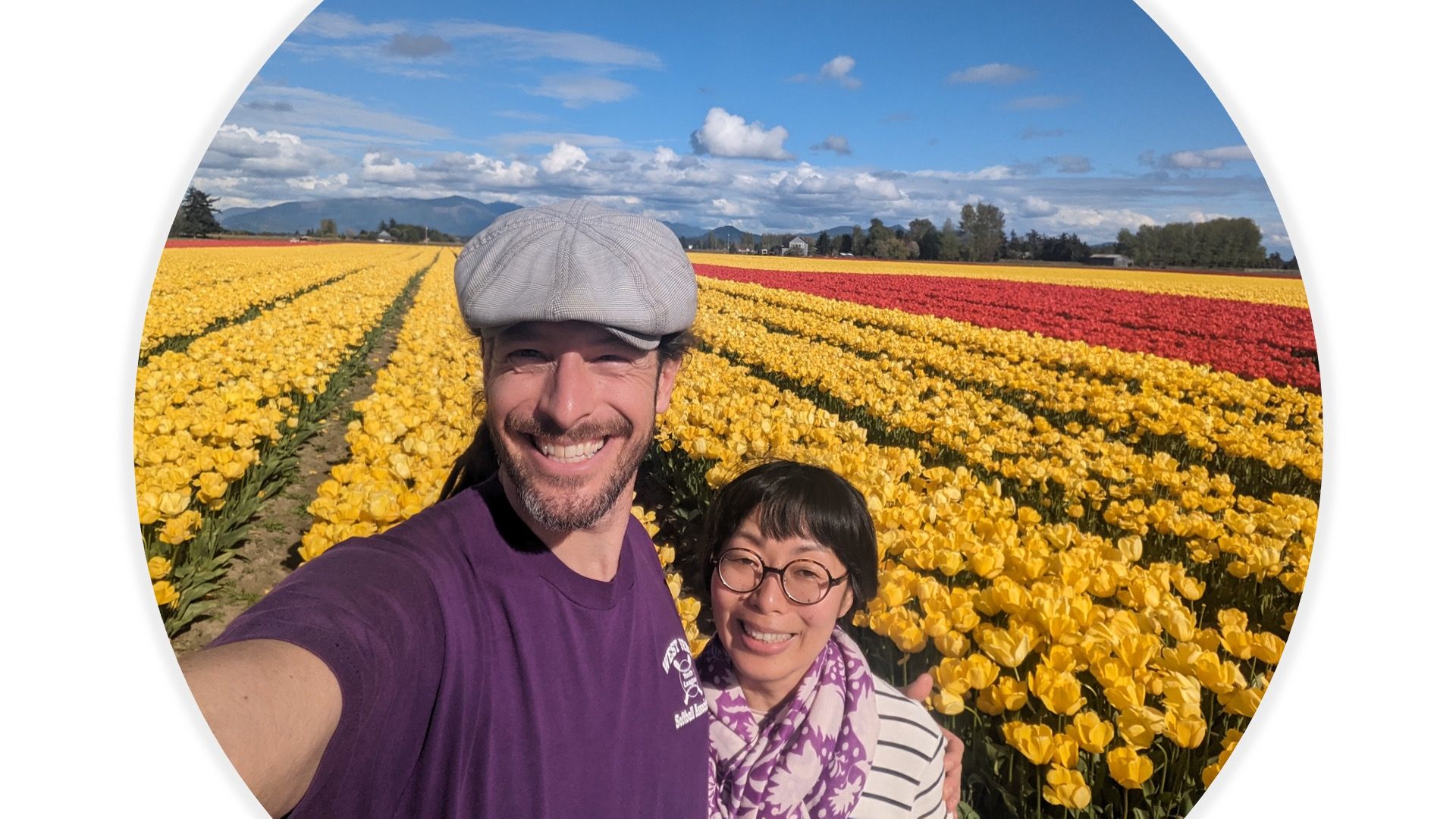 Two people smiling in a field of yellow tulips during the Skagit Valley Tulip Festival.