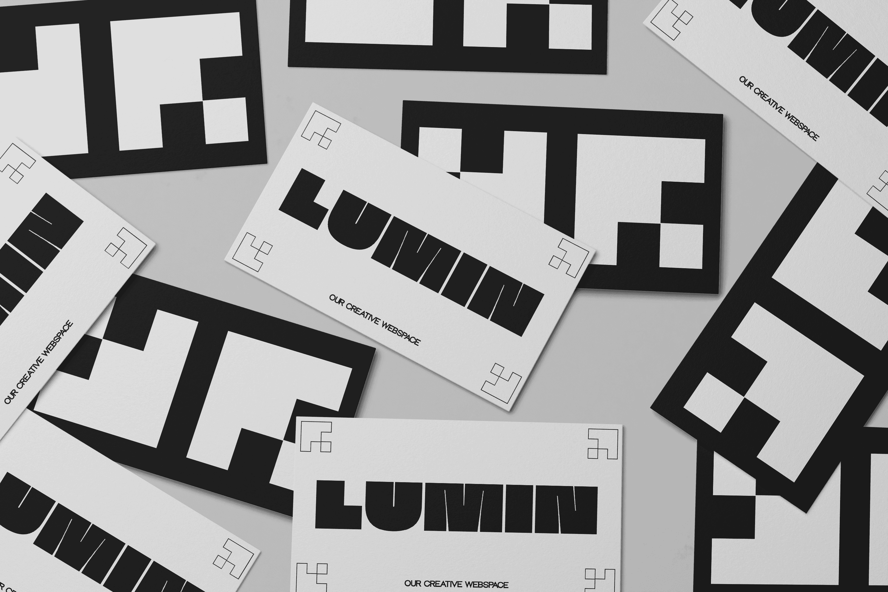 The image shows several black and white business cards scattered on a surface, featuring the bold, uppercase word "LUMIN" and the phrase "OUR CREATIVE WORKSPACE" alongside abstract geometric patterns.
