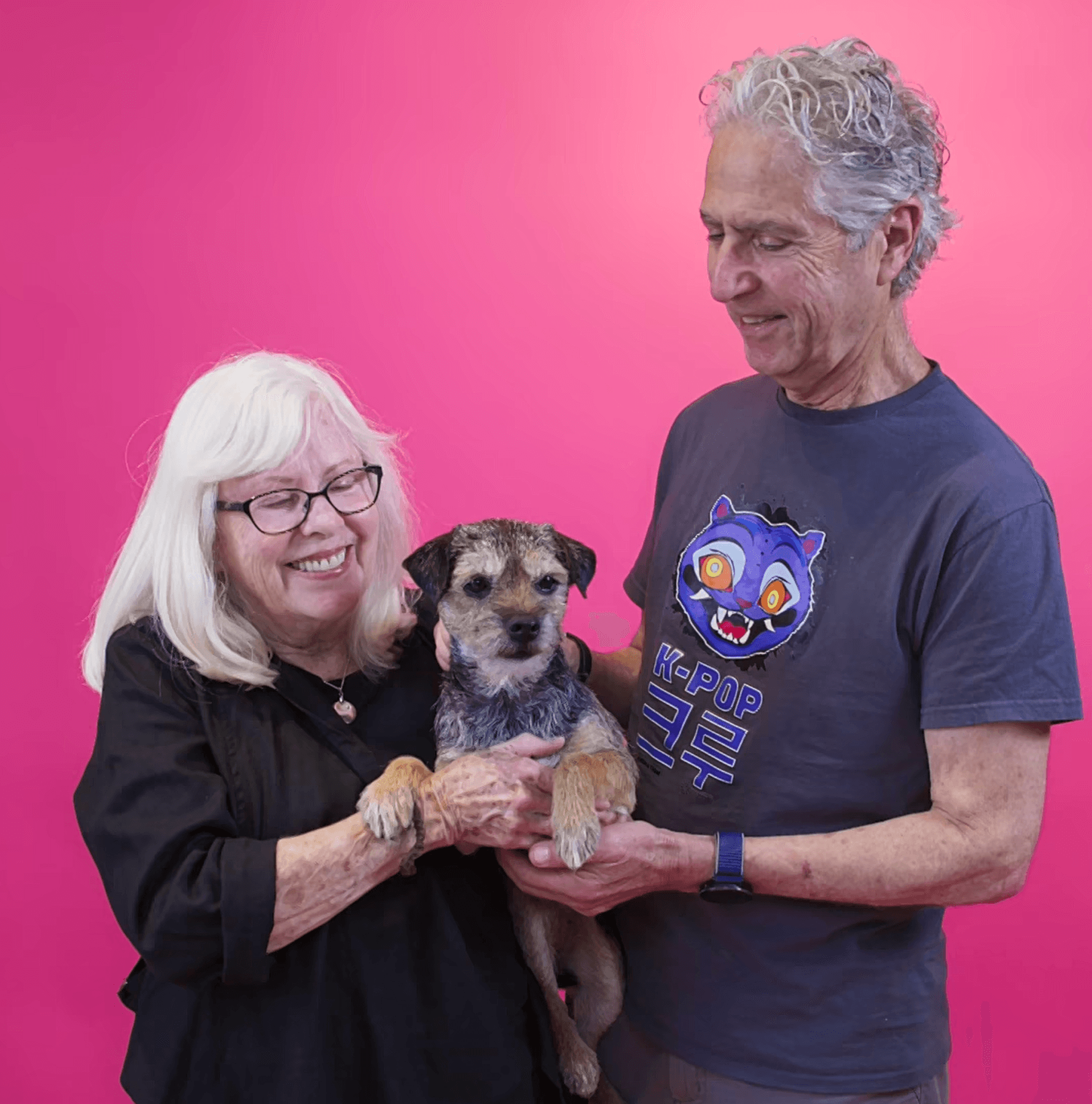Heartwarming photo of an older couple cuddling their freshly groomed dog to highlight affection, comfort, and trusted grooming results.