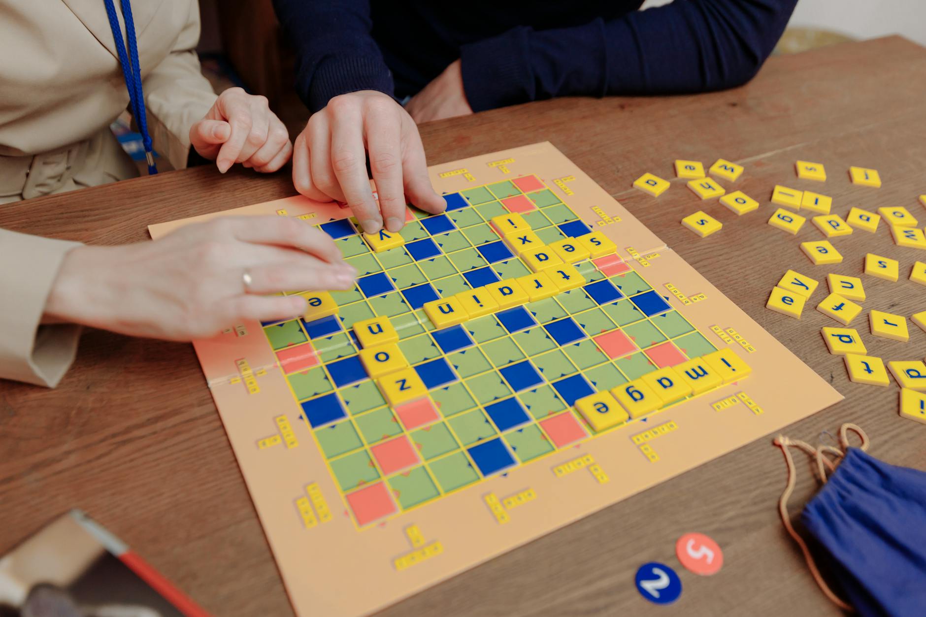 A young girl excitedly holds up a tablet displaying interactive letter recognition games in a bright classroom setting.