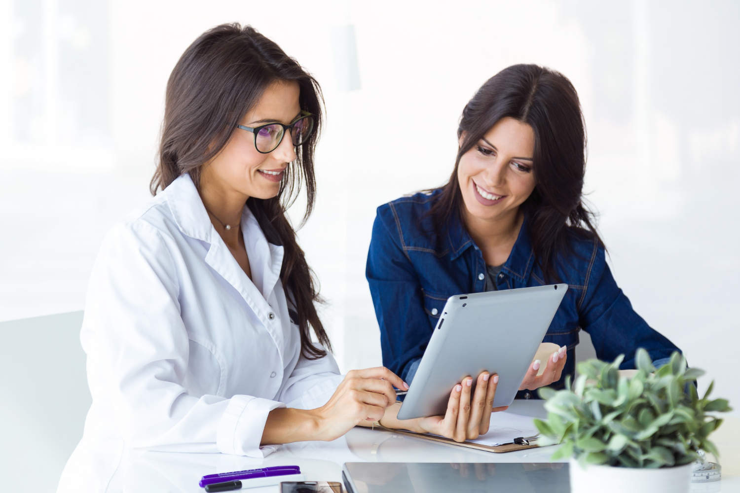 A female doctor showing a tablet device to a young woman.