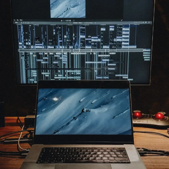 A laptop and monitor with video editing project visible on screen