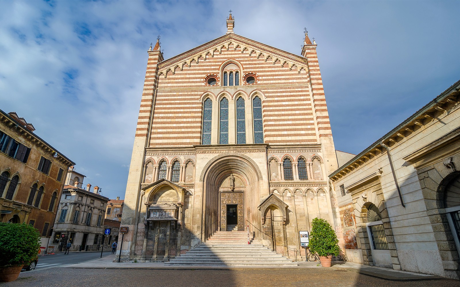 San Fermo Maggiore kirkens facade i Verona, Italien, med stribet murværk og buet indgang.