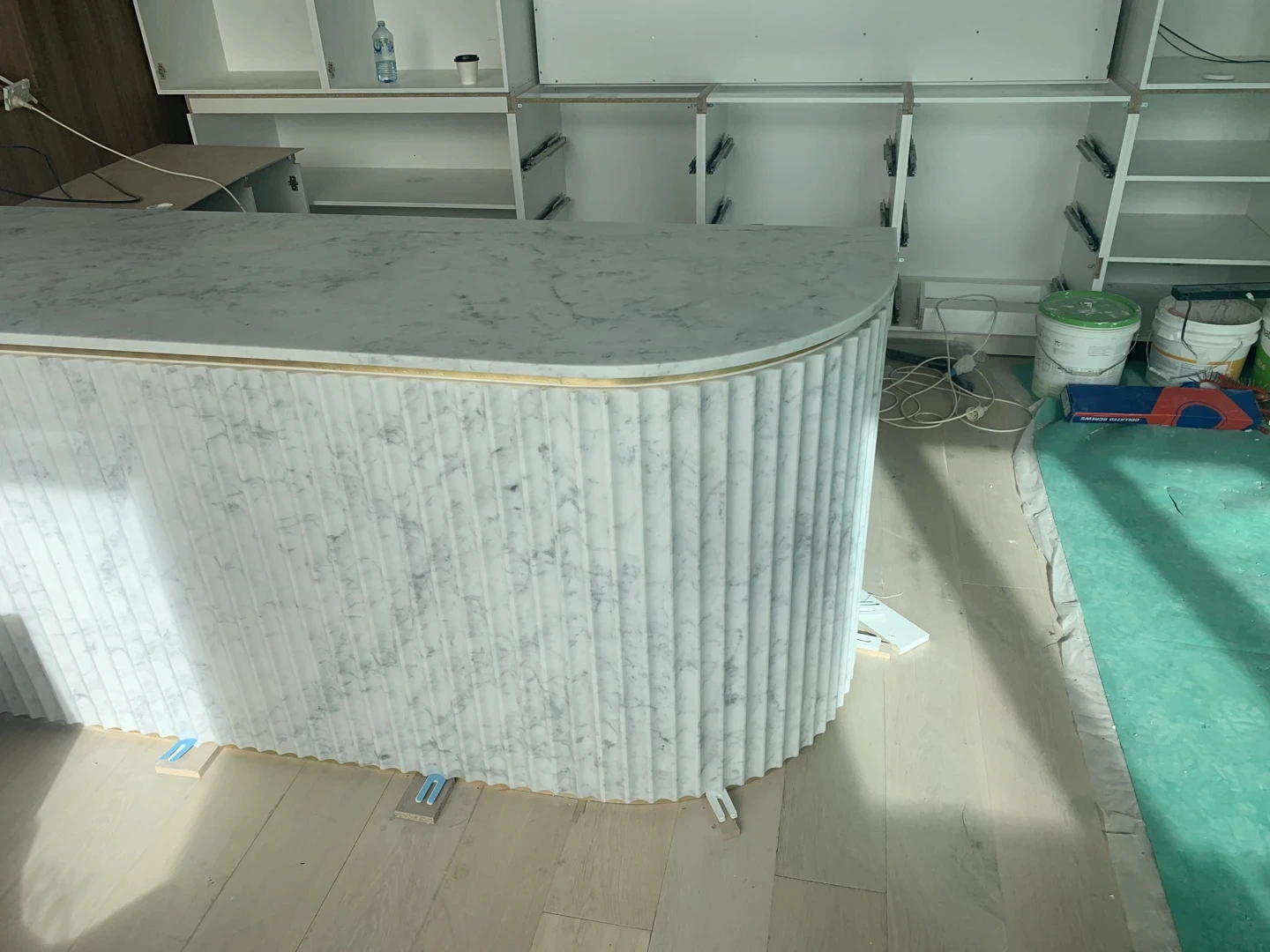 Curved marble fluting waterfall bar counter with vertical ribbed natural stone cladding and a rounded polished top for a bold sculptural bar feature.