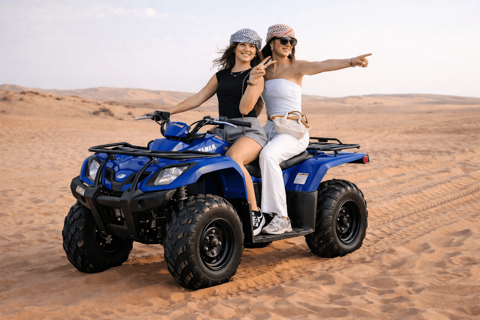 Two women riding a Yamaha 350cc ATV during a Dubai desert safari quad biking experience with Dune Quest Tours