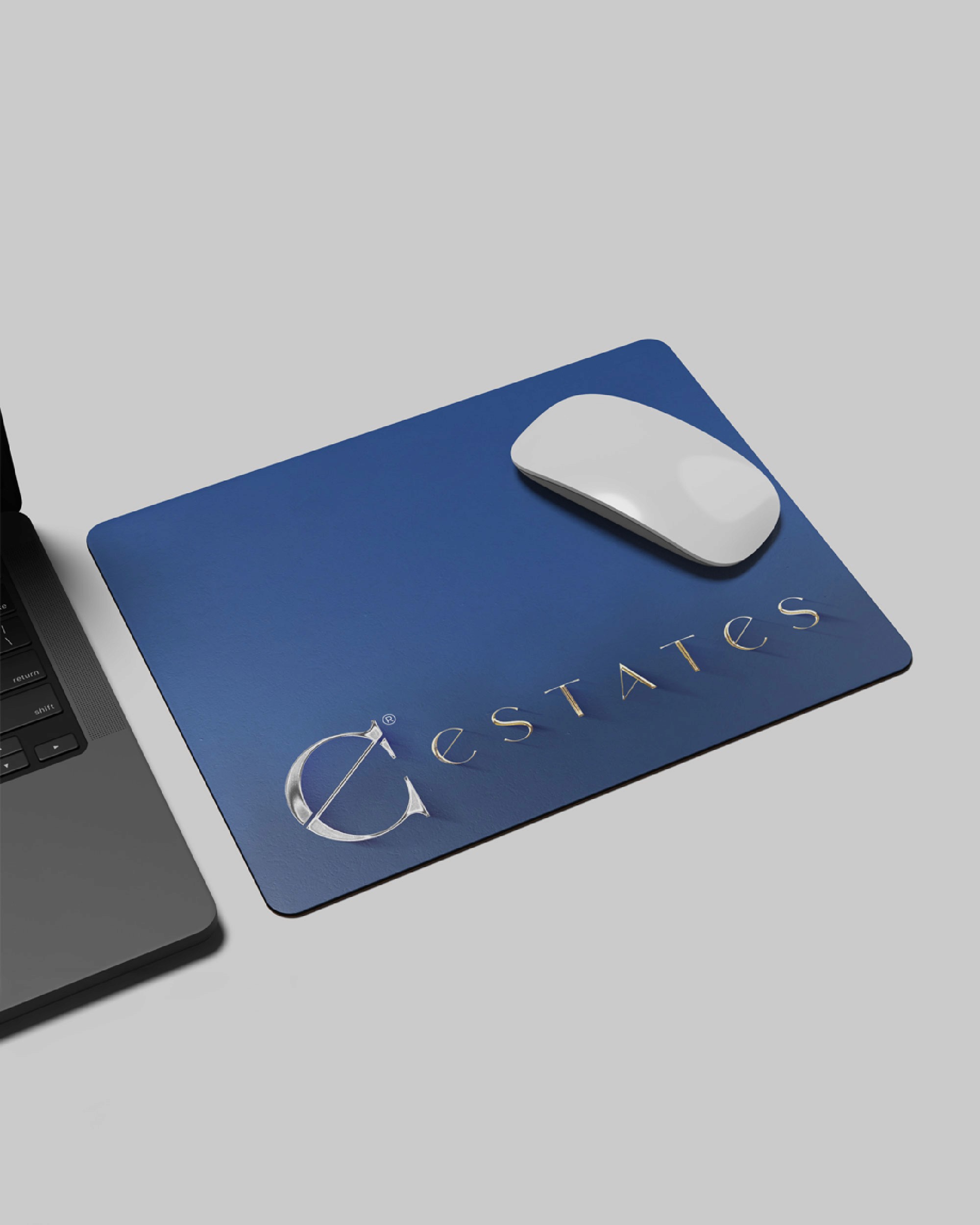 Navy Clarion Estates desk mat with the metallic Estates wordmark beneath a white mouse.