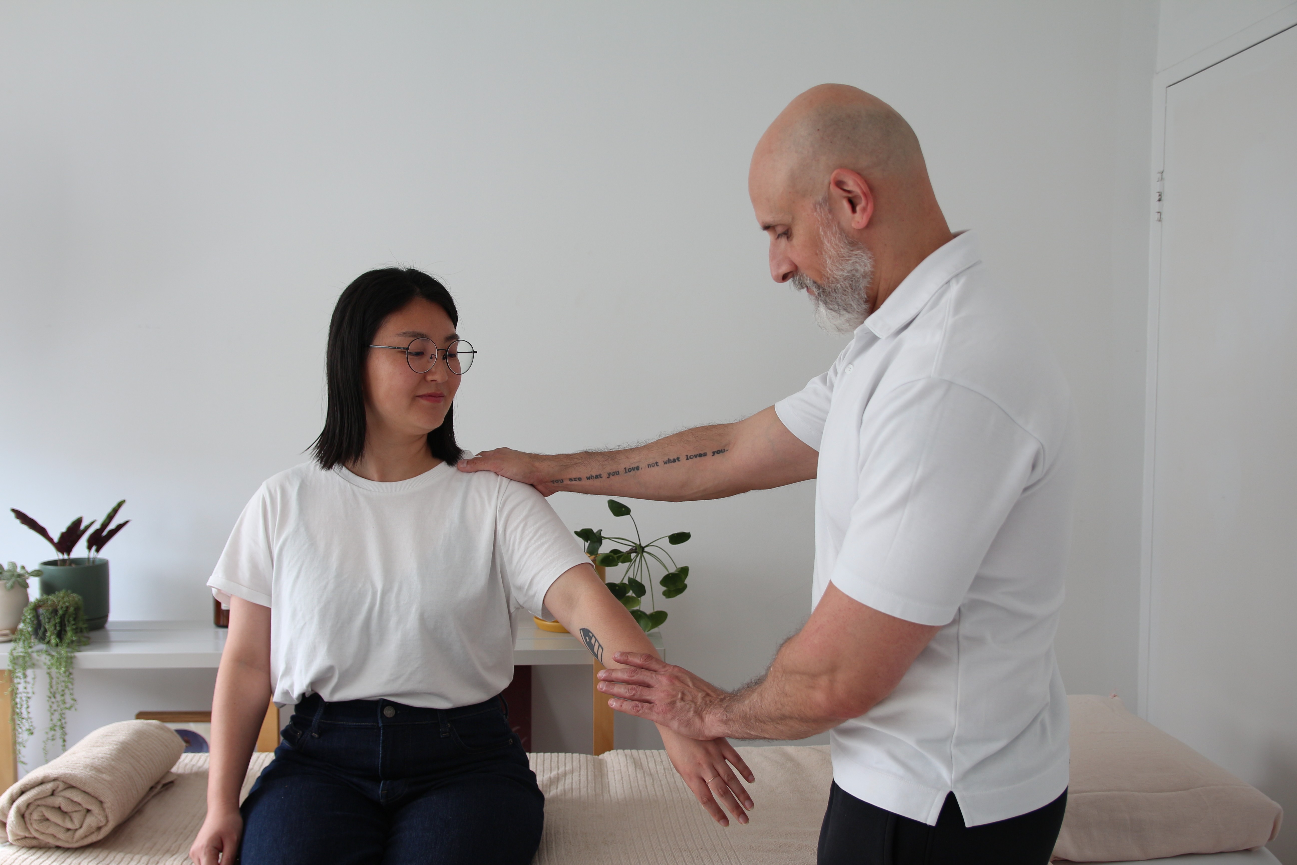 Woman in a towel and head wrap applying skincare cream in a cozy bedroom