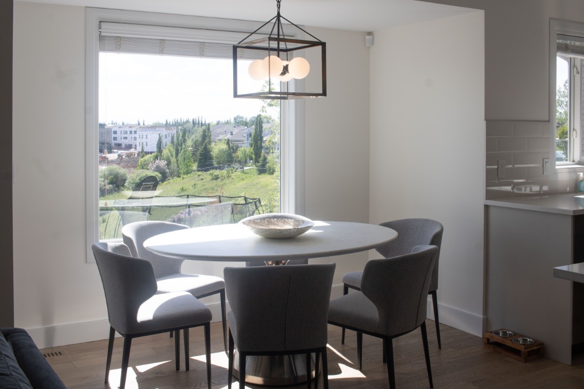 Image of Modern dining area with round table, gray chairs, and pendant light, KHD Homes interior design.
