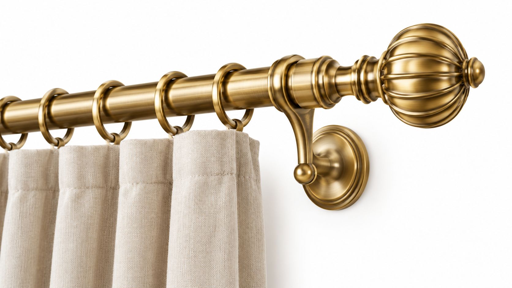 A close-up of an elegant brass curtain rod featuring a decorative finial and beige fabric curtains.