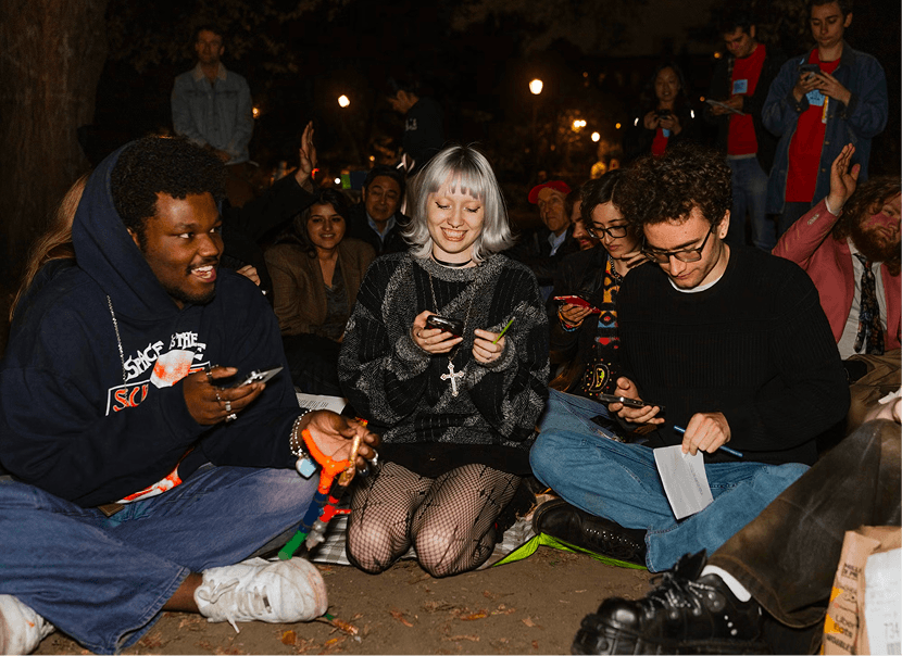People seated on the ground holding their cellphones
