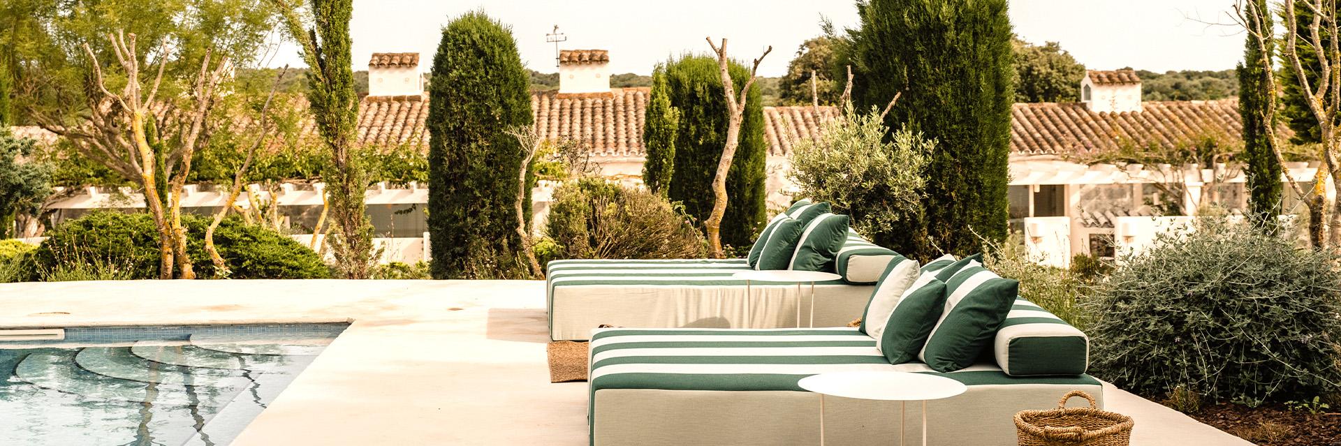 A bride and groom hold hands tenderly, the bride's bouquet of dried flowers hanging low. They stand in a softly lit, elegant interior, conveying romance.