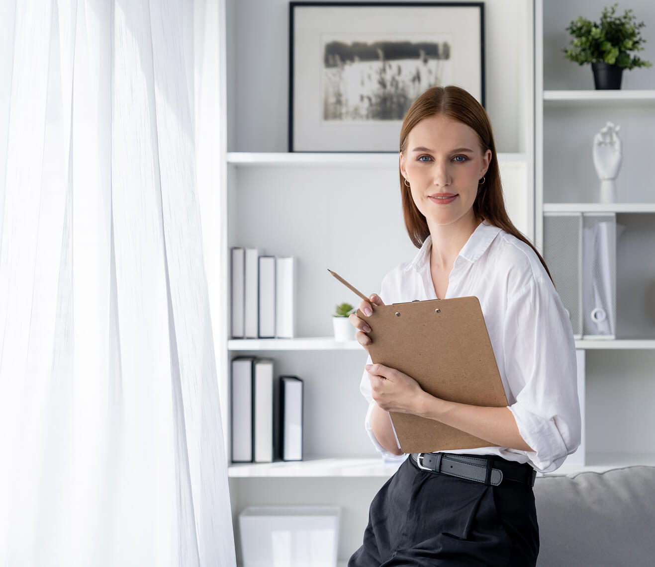 Therapist sitting on a sofa and taking notes on a clipboard during a session